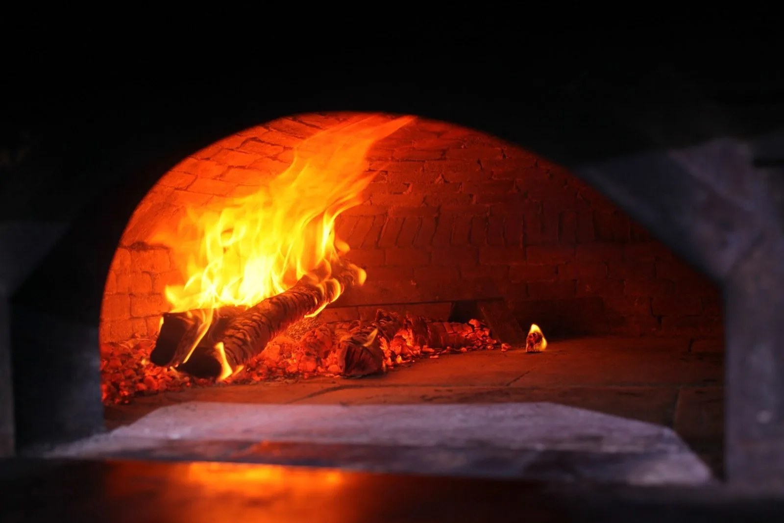 Fuoco acceso dentro un forno a legna in mattoni pronto per la pizza