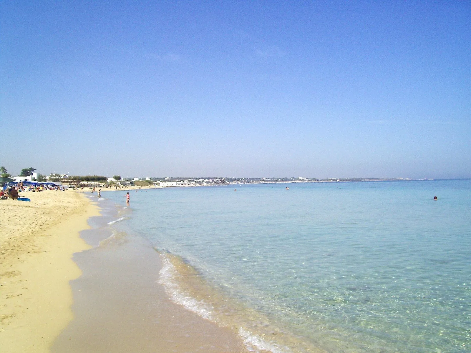 Spiaggia di sabbia dorata con acqua bassa e trasparente sul litorale del Capitolo a Monopoli