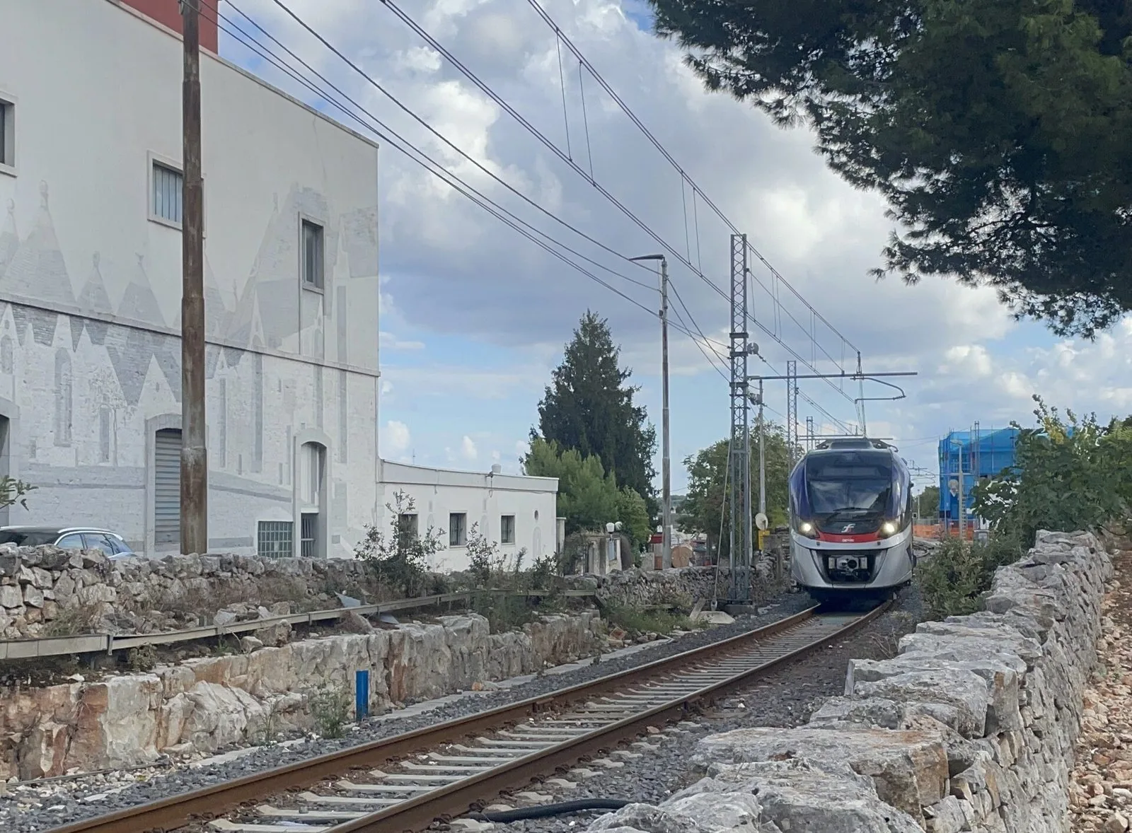 Treno regionale delle Ferrovie del Sud Est tra muretti a secco nella Murgia dei trulli